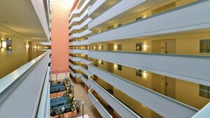 A multi-story hotel interior with a central atrium, balconies, and a ground-level outdoor area with plants. - Luxury 3BR/3BA Condo with Panoramic Ocean Views! (North Myrtle Beach)