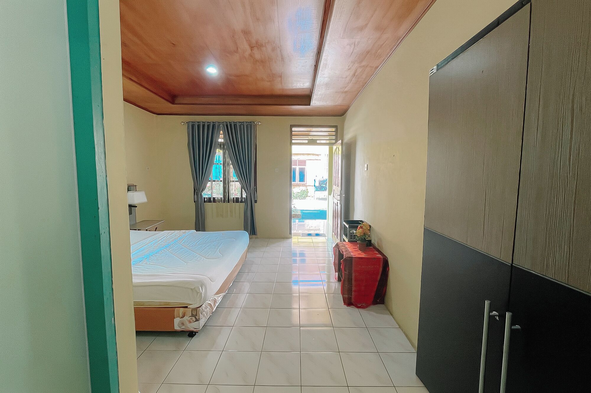 Un pasillo estrecho que conduce a un dormitorio con una cama, una mesita y un armario.