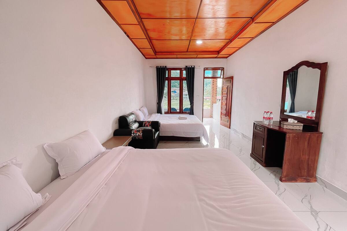 Habitación de hotel con dos camas, un aparador de madera, un espejo y vistas al exterior.