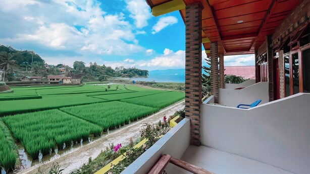 Un balcone con vista su campi di riso verdi e una catena montuosa in lontananza.