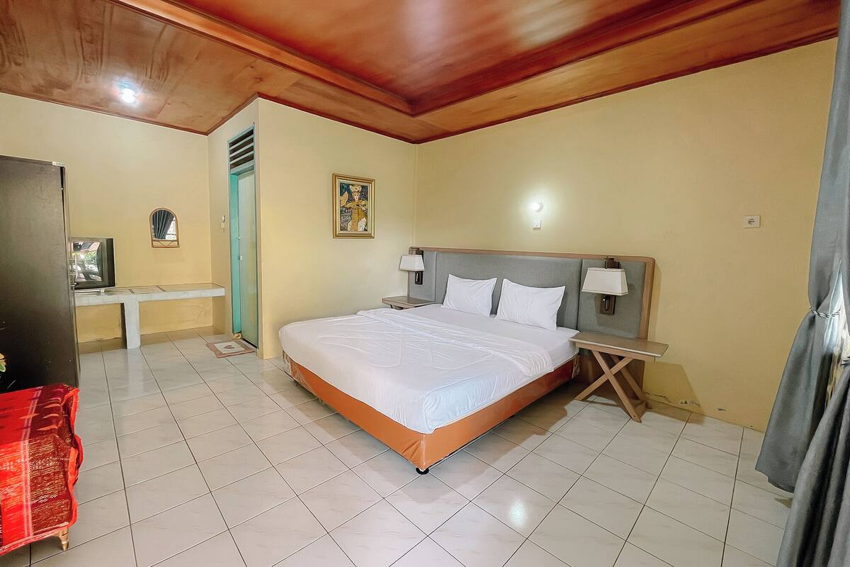 Una habitación de hotel con una cama grande, una mesita de noche, un escritorio pequeño y un espejo.