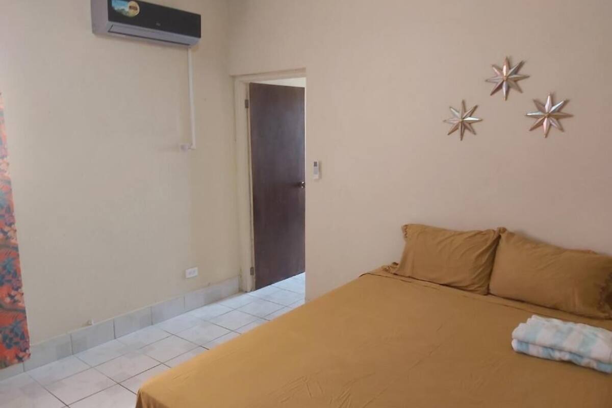 A bedroom with a bed, a door, and a wall-mounted air conditioner.