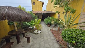 A courtyard with a thatched roof, potted plants, and a tiled floor. - Residencial Valda, your accommodation in Cabo Frio. (Cabo Frio)