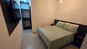 A bedroom with a bed, a nightstand, and a closet. - Residencial Valda, your accommodation in Cabo Frio. (Cabo Frio)