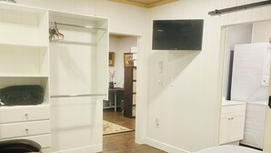 A bedroom with two beds, a ceiling fan, a TV, and a wardrobe.