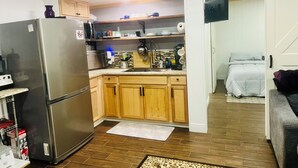A compact kitchen with wooden cabinets, a stainless steel refrigerator, and a microwave.