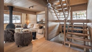 A cozy wooden interior with a fireplace, a sofa, fluffy poufs, and a wooden staircase. - Chalet Quatre Coeurs with sauna in Saint Gervais (Saint-Gervais-les-Bains)