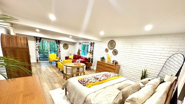 A modern bedroom with a bed, a sofa, a dining table, and a desk.