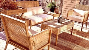 A covered outdoor seating area with wicker furniture and a brick wall.