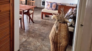 A modern kitchen with built-in appliances, a dining area with wooden furniture, and a living space with a sofa and decorative pillows.