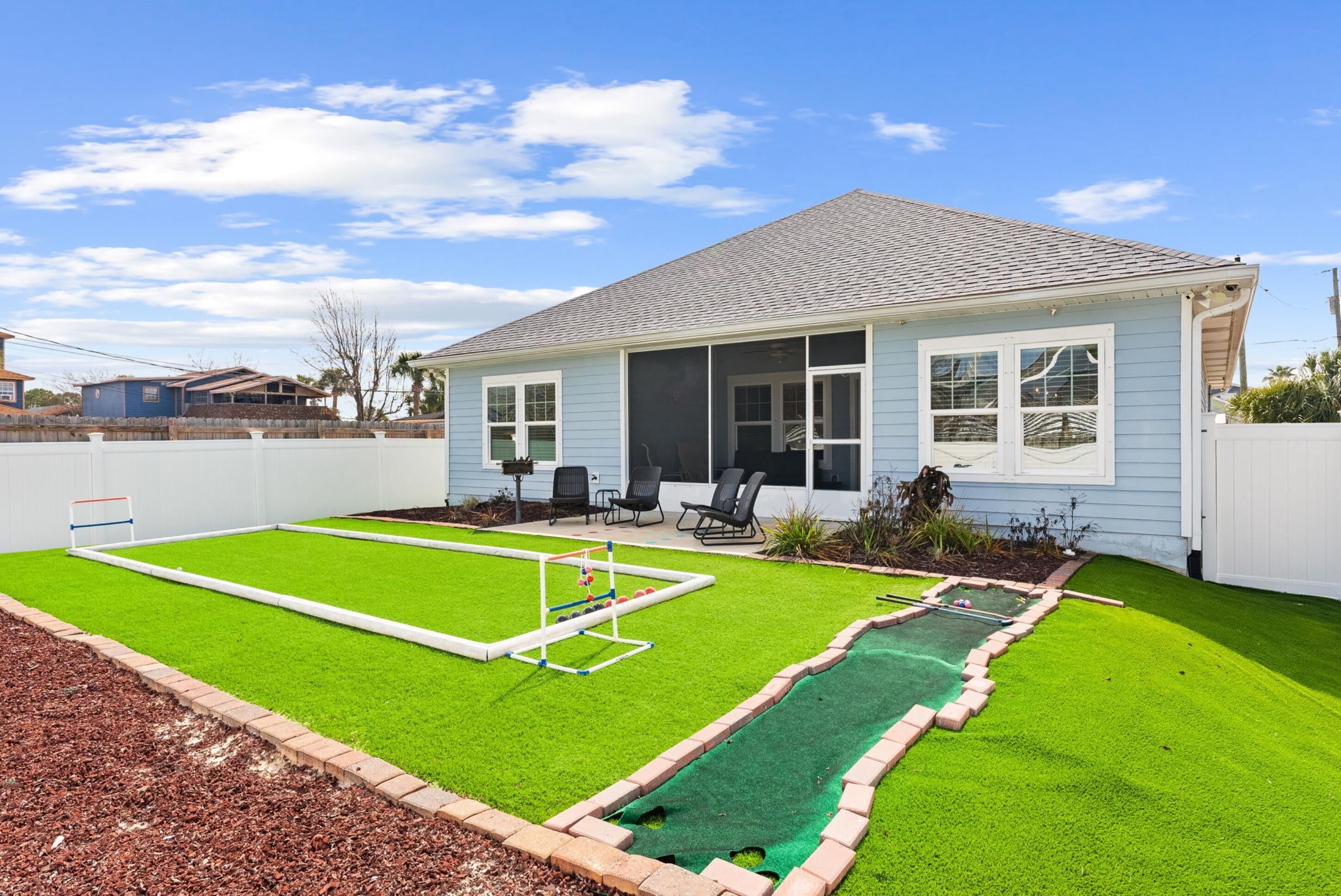 Une maison avec un jardin comprenant une petite piscine, une pelouse et un espace patio avec des chaises.