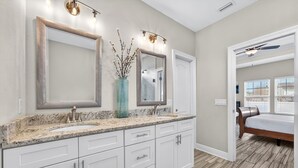 A bathroom with a large mirror, two sinks, a vase with branches, and a ceiling fan. - Beach House - Tropic Like It's Hot (Panama City Beach)