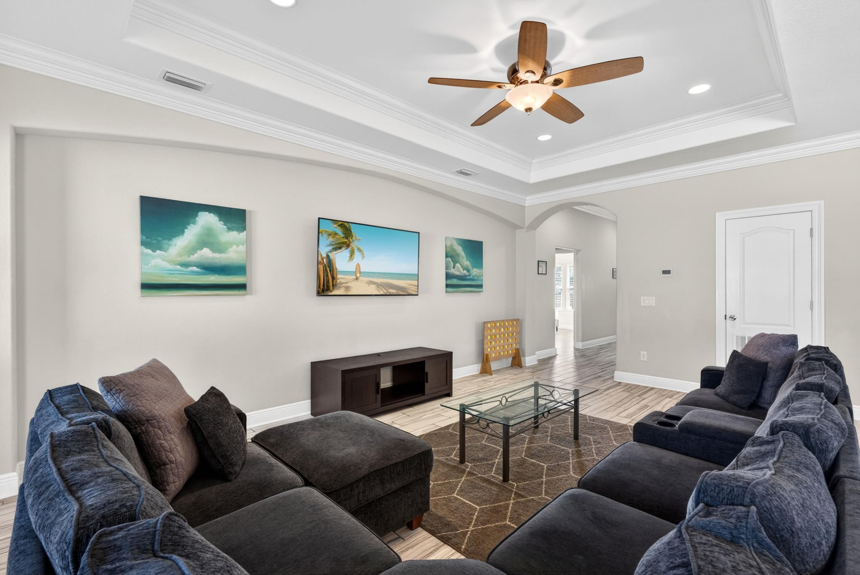 A modern living room with a sectional sofa, a glass coffee table, and artwork on the walls.