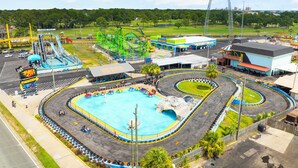 A theme park with a large roller coaster, a water park area, and a parking lot. - Beach House - Tropic Like It's Hot (Panama City Beach)