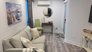A modern living room with a striped sofa, a round mirror, and a wooden coffee table. - Cozy 1-bedroom apartment in serene Rehoboth Beach with AC (Rehoboth Beach)