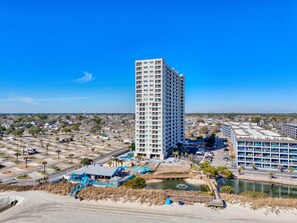 A high-rise hotel with multiple floors, a parking lot, and a beach area with a pool. - The Coastal Nook (Horry County)