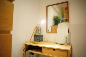 Un escriptori de fusta amb un mirall, una làmpada i un ordinador portàtil.