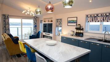 Une cuisine moderne avec un îlot central, des meubles bleus et une vue sur la mer.