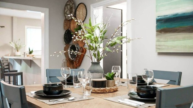 Une table à manger dressée avec des assiettes, des verres et un vase rempli de fleurs.