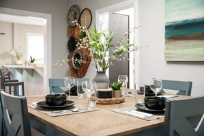 A dining table set with plates, glasses, and a vase with flowers.