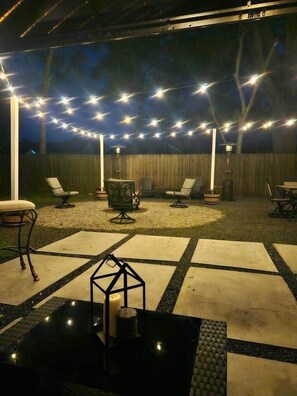 An outdoor patio area with string lights, seating, and a decorative lantern. - Quaint house, king bed 2min from down town (Aiken)