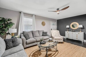 A living room with a sofa, armchair, coffee table, and a dresser with lamps. - Quaint house, king bed 2min from down town (Aiken)