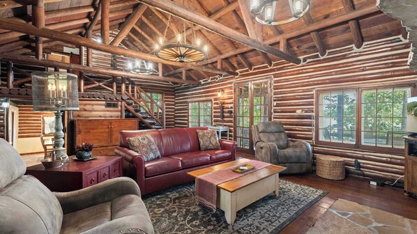 A log cabin interior with a leather sofa, a wooden coffee table, and a fireplace.