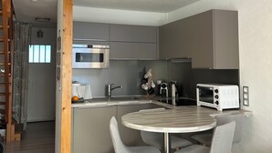 A modern kitchen with a central island, grey chairs, and a wooden ceiling. - Cosy duplex in the Haut-Jura with detached garage. (PREMANON)