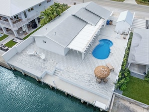 Ein Anwesen am Wasser mit Schwimmbad, Sitzgelegenheiten im Freien und einer überdachten Terrasse.