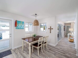 A dining area with a wooden table and chairs, a hanging light fixture, and a wall-mounted cross. - Beautiful Key Haven Home with Pool, Dock &boat lift (Key West)