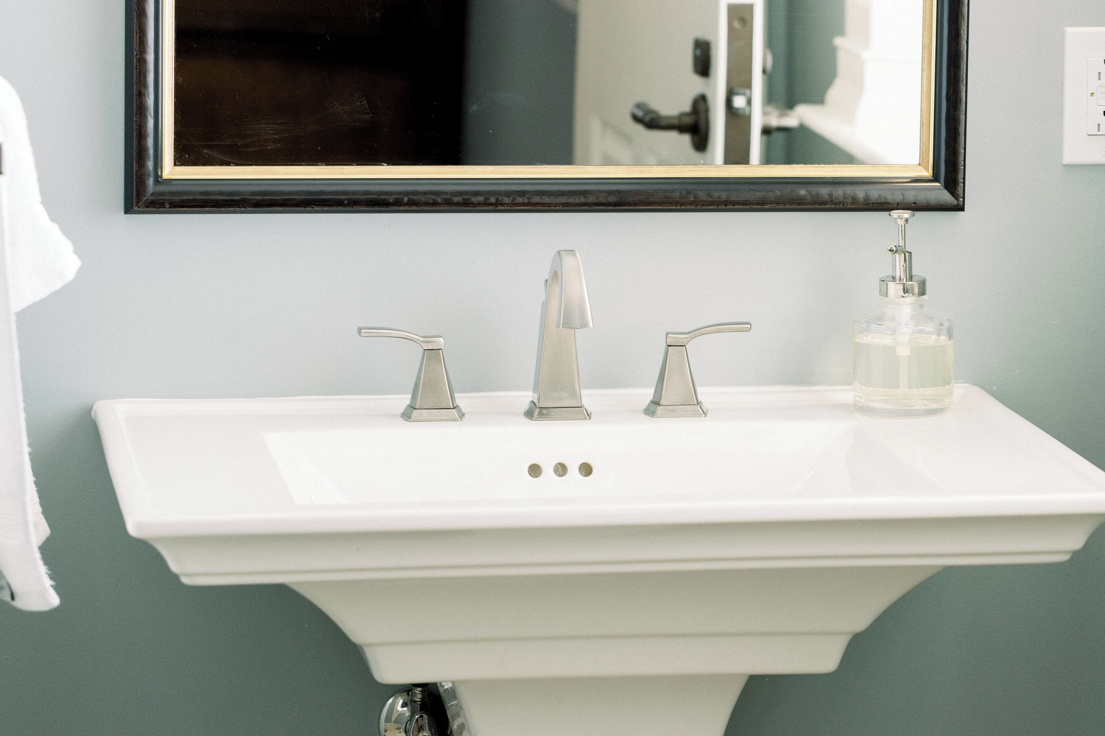 A white bathroom sink with a single faucet and a soap dispenser.