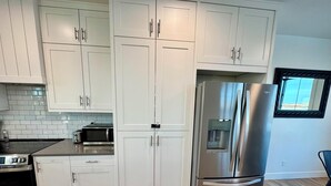 A modern kitchen with white cabinets, stainless steel appliances, and a built-in water dispenser. - 4 bedrooms & attached bathrooms, EV charge, water purifier, gas fireplace, games (Rexburg)