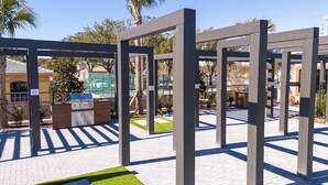 Un espace extérieur comprenant un barbecue, un chemin pavé et une structure métallique.