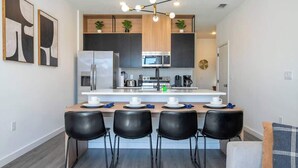 Une cuisine moderne avec un îlot central, des chaises noires et une table à manger.