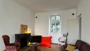 A living room with a fireplace, a red sofa, a wooden coffee table, and a chair. - Mansion with swimming pool (Saint-Paul-lès-Dax)