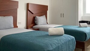 A hotel room with two beds, each with a wooden headboard, white bedding, and teal blankets. There is a wardrobe with a mirror and a window with blinds. - 508 New apartment, in Real Real View area 2 bedrooms (Zapopan)