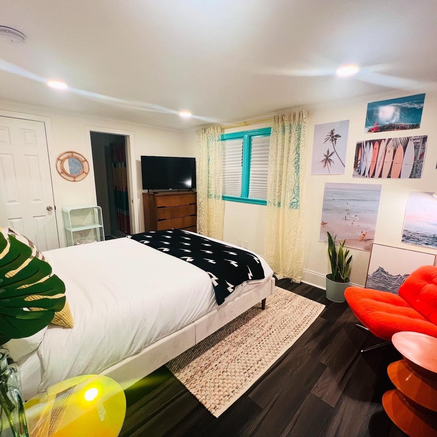 A bedroom with a bed, a television, a window with curtains, and various wall decorations.