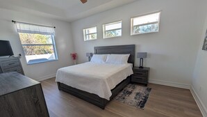 Ein Schlafzimmer mit einem Bett, Nachttischen, einem Schreibtisch und einem Deckenventilator.