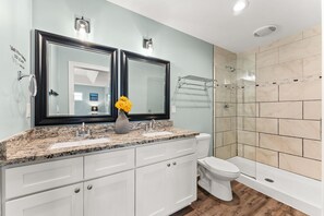 A bathroom with a double sink vanity, a toilet, and a walk-in shower. - Beach House - Sunset by the Sea (Panama City Beach)