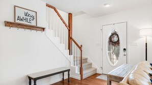Eine Treppe mit Holzwertlauf, einer Bank, einer Tür mit dekorativem Glasfeld und einem an der Wand befestigten Schild.