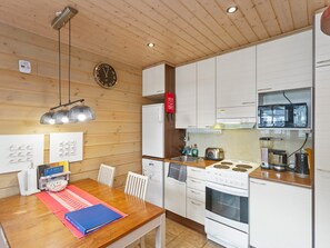 Une cuisine de taille réduite avec un plafond en bois, des placards blancs, une cuisinière et un évier.