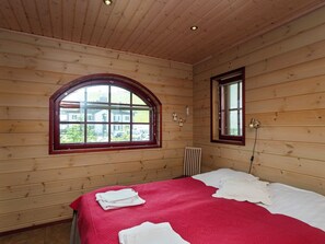 Une pièce en bois avec un lit, une fenêtre et un radiateur.