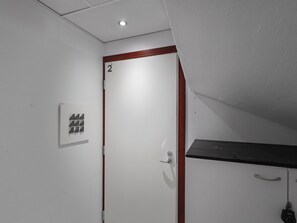A white door with a red frame, a small sign with four arrows, and a ceiling light. - Levin otava 2 by Interhome (Kittilä)
