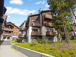 A multi-story building with balconies, a stone facade, and a pathway leading to the entrance. - Levin otava 2 by Interhome (Kittilä)