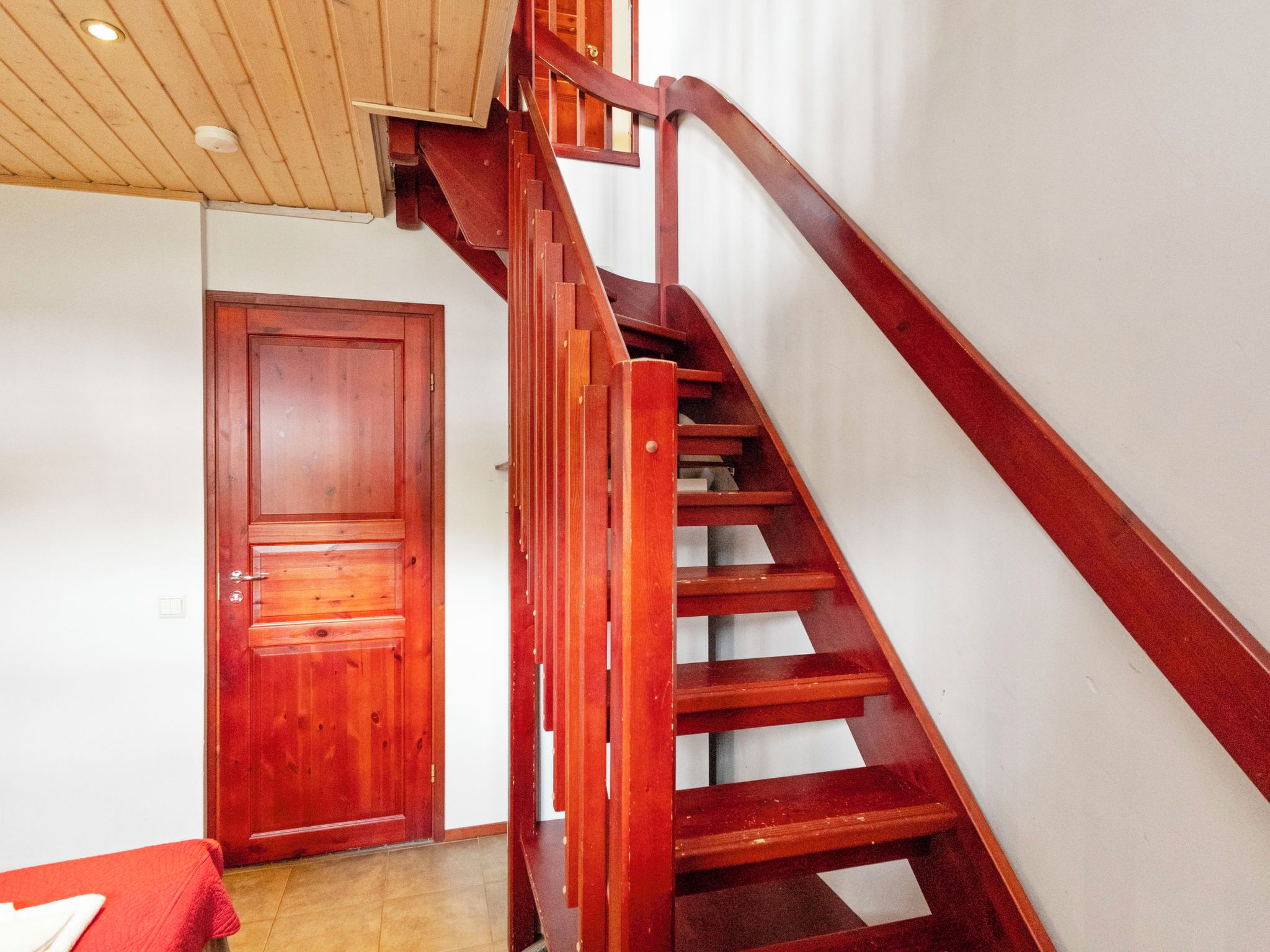 A wooden staircase with a handrail leading to a door.