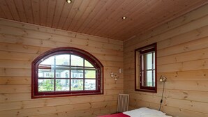 Ein Zimmer mit Holzwänden, einem Bett, einem Fenster und einer Heizung.