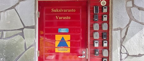 A red door with a sign reading 'Suksivarasto Varasto' and a blue and yellow triangle symbol.