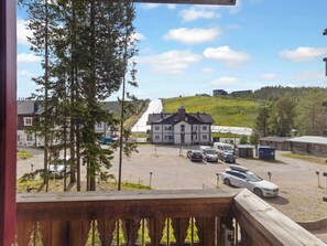 Un hôtel doté d’un parking, un bâtiment avec un toit en pente et une vue sur une colline bordée d’arbres.