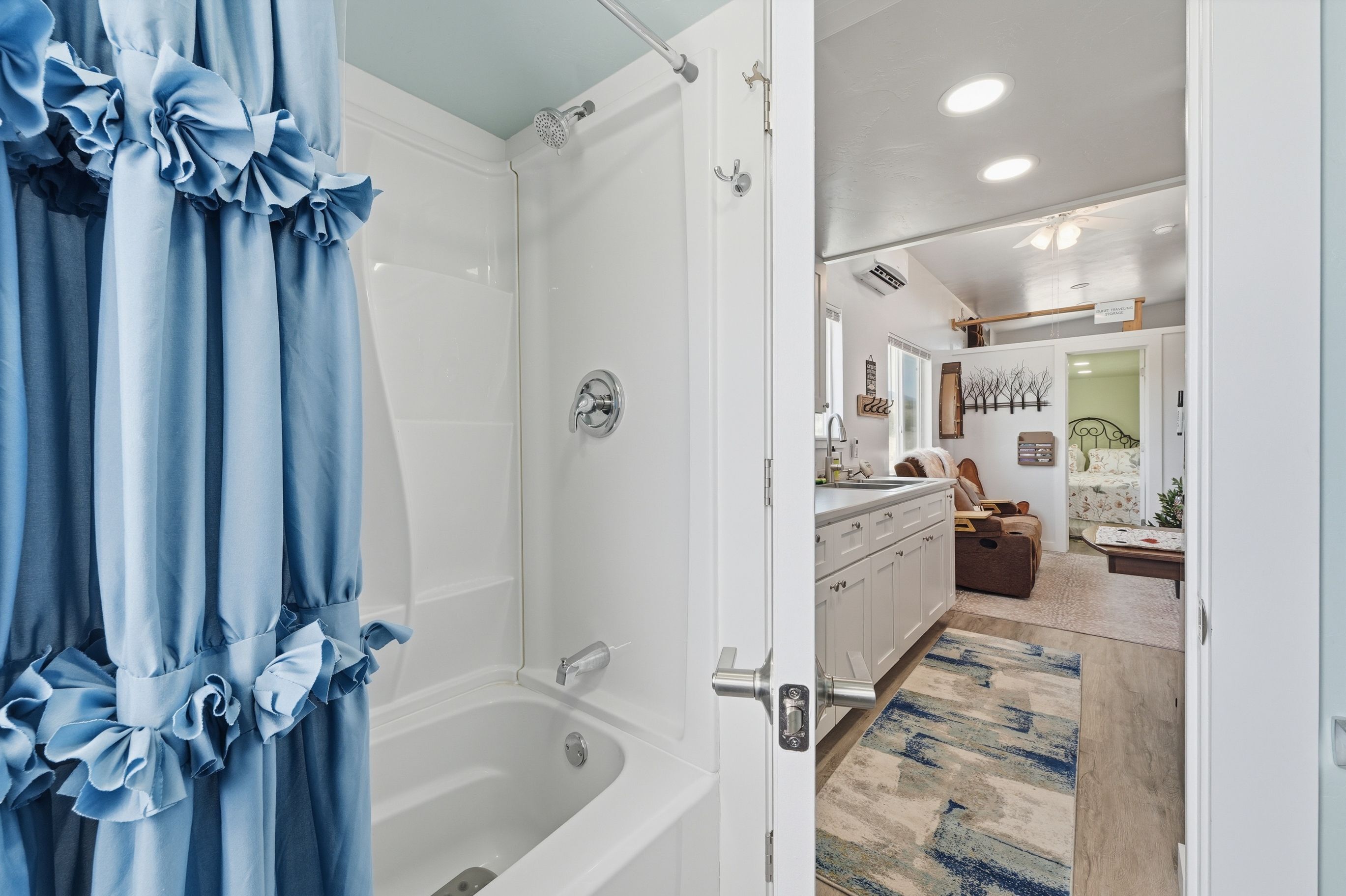 Un baño con bañera, ducha y una puerta que da a una sala de estar con sofá y mesa de centro.