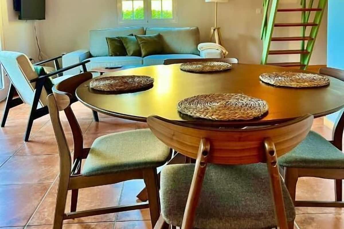Un comedor con una mesa redonda, sillas e iluminación colgante.